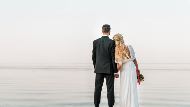 Back-view-of-wedding-couple-standing-on-beach-with-2022-01-18-23-38-55-utc